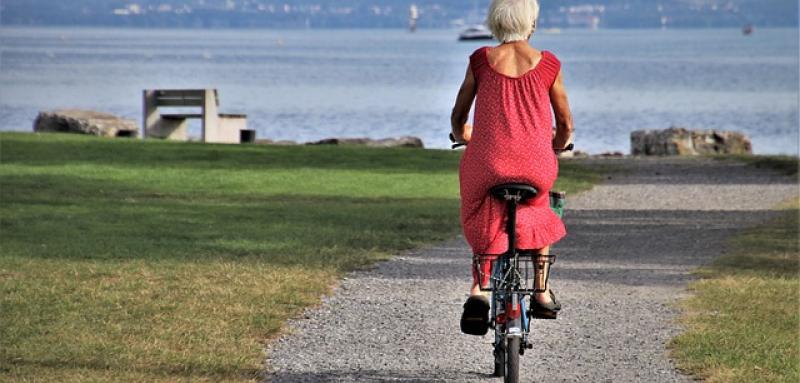 Older woman rides bicycle to the beach